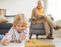 A grandmother watching her grandkid color